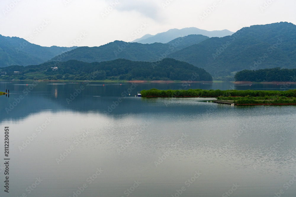 Fototapeta premium Panoramic Lake View with Deep Blue Mountain Reflection and Floating Vegetation