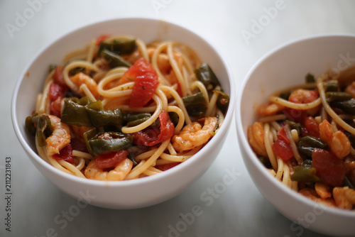 Bowl with spaghetti, shrimps, tomatoes and herbs