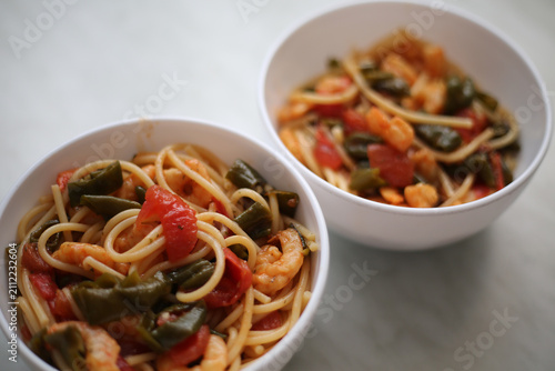 Bowl with spaghetti, shrimps, tomatoes and herbs