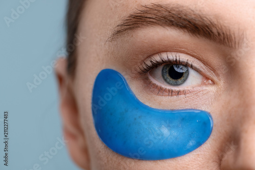 Фотография Beautiful woman with eye patch on light blue background, closeup