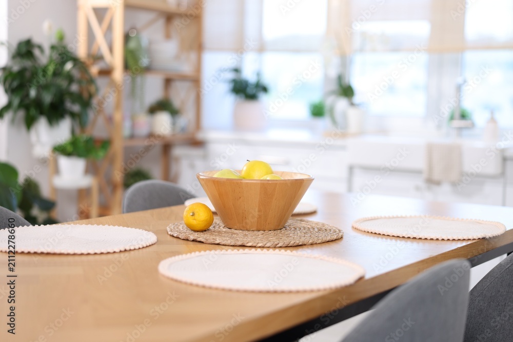 Fototapeta premium Bowl with fruits on wooden table and chairs in kitchen