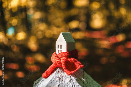 Model house with red scarf symbolizes passive house heating and insulation in response to energy crisis