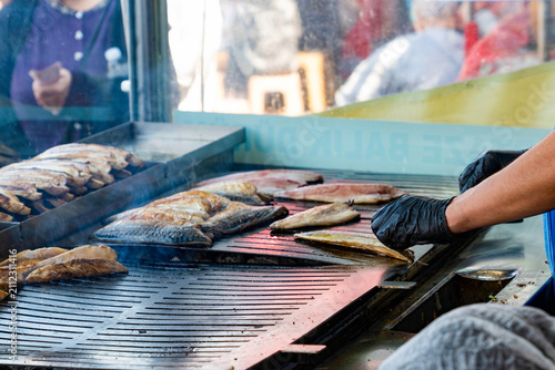 Chef grilling mackerel fish fillets on outdoor grill for traditional fish sandwich in Istanbul, Turkey