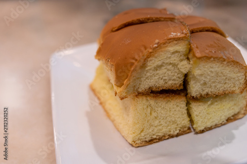 Freshly baked soft milk bread loaf sliced into four thick pieces and served on a white plate. 