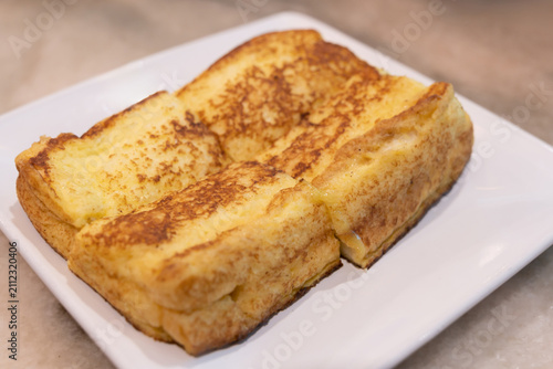 Golden French toast slices spread with kaya jam (coconut jam) on a white ceramic plate