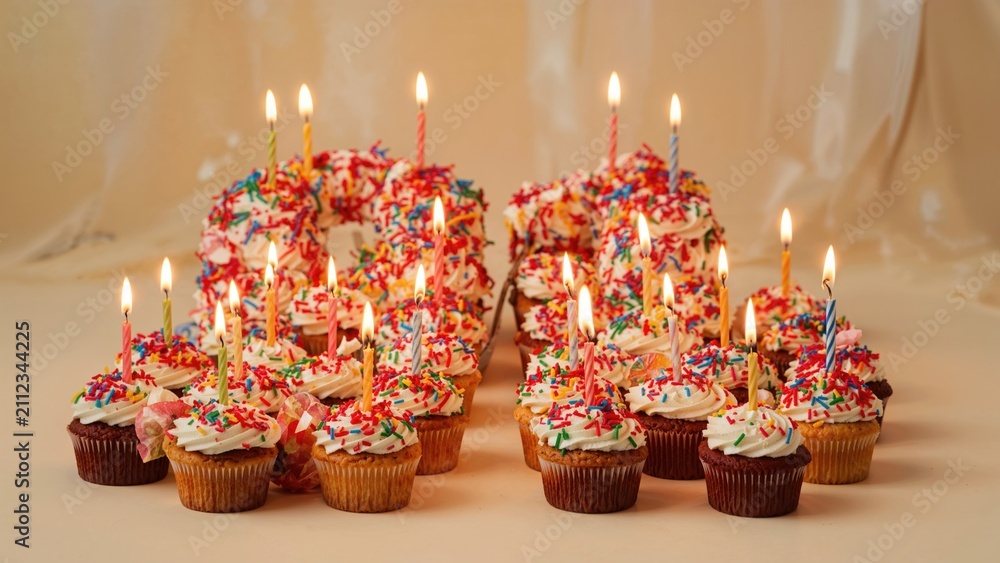 Obraz premium Birthday cupcakes with lit candles, colorful sprinkles, and festive decorations. Celebration and party concept. Cake and baking quantity. The concept of birthday festivities.