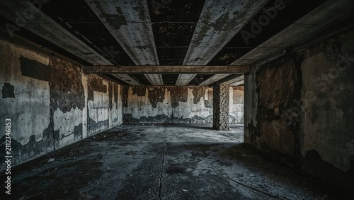 Abandoned concrete parking garage with deteriorated walls and ceiling, dark and empty, showing signs of neglect and decay.