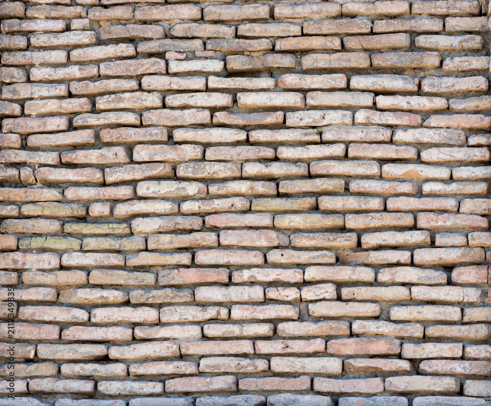 Obraz premium Texture of an old brick wall made of light brown and beige bricks. The rough surface with natural imperfections is perfect as a background for architectural and graphic design projects.