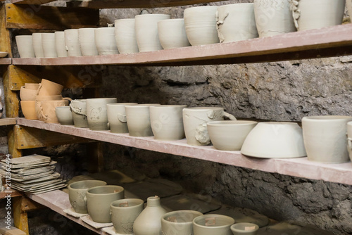 Photography Clay pottery displayed on shelves in a workshop, showing various shapes and size