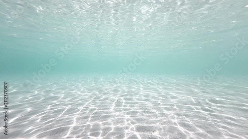 Bright shallow underwater sandy seabed with shimmering sunlight wave patterns in turquoise ocean, natural marine background, 4K_1_IMG_5271_20s_0,03.MOV.mov