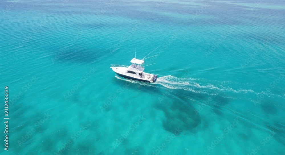 Naklejka premium A white fishing boat speeds across crystal clear turquoise ocean waters under a bright sky