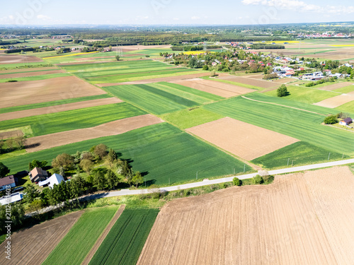 Canvas Print Aerial view of agricultural fields patchwork in rural landscape with village, gr