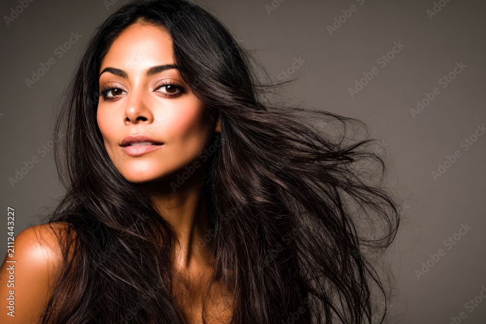 Naklejka premium A female model with long silky brown hair showcases beauty and hair care concepts highlighting shine, volume, and healthy natural movement in a studio setting.