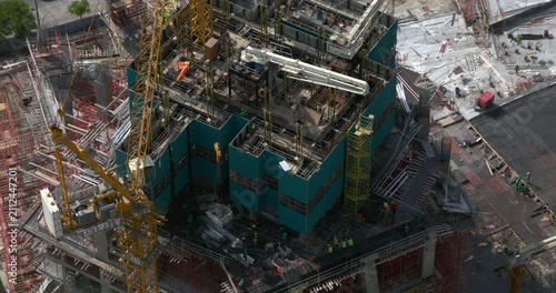 Timelapse of a yellow tower crane rotating at a high rise building construction site, its long jib swinging above the concrete structure
