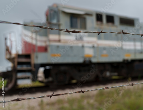 Barbed wire preventing access to retired freight locomotive awaiting further use or dismantling on an industrial site in North Texas USA,