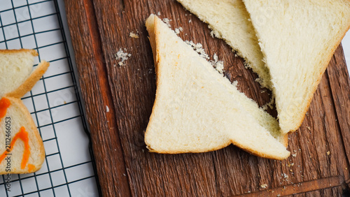 A slice of bread is cut in half and placed on a wooden cutting board