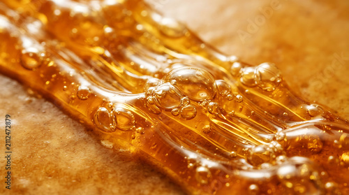 Golden honey dripping thickly from honeycomb, close-up texture