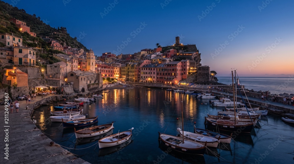 Fototapeta premium Picturesque Mediterranean Coastal Village at Dusk with Colorful Hillside Homes, Charming Harbor Filled with Fishing Boats, Warm Lights Reflecting on Calm Sea and Vibrant Sunset Sky Creating a Peaceful
