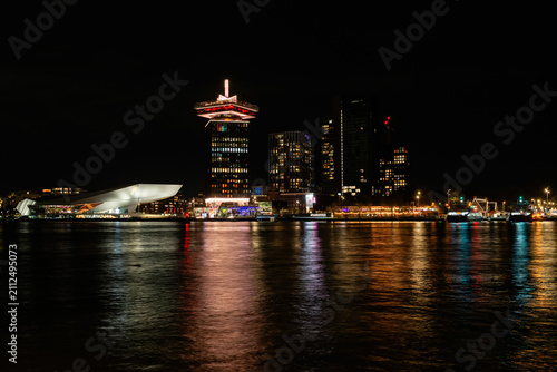 AMSTERDAM, NETHERLANDS - OCTOBER 30, 2025: A panoramic night view across the IJ river of the illuminated Amsterdam North skyline featuring the Eye Filmmuseum and A'DAM Lookout tower