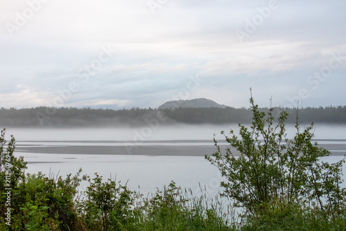 Obraz na plátně Mist rising off a wide river and gravel bars under a cloudy twilight sky with gr