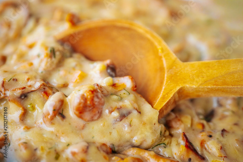 Bild auf Leinwand A macro close-up of chanterelles in a rich creamy herb sauce with a warm wooden spoon, creating a rustic culinary composition