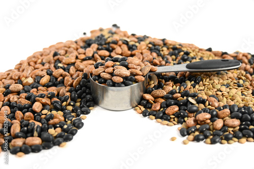Obraz na plátně Several types of beans filling a silver measuring cup that is sitting in a pile