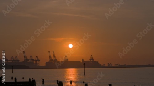 Sunset over harbor cranes and calm water