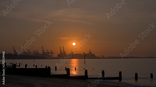 Sunset over harbor with cranes and calm water