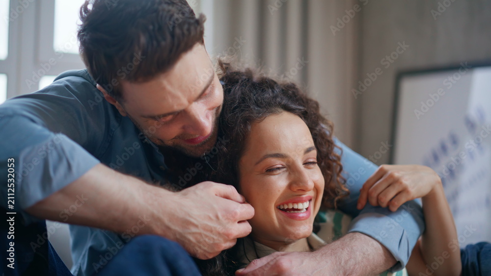 Fototapeta premium Smiling couple bonding home closeup. Boyfriend embracing happy girlfriend sofa.