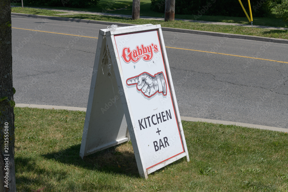 Obraz premium a-frame boulevard or road side sign with manicule near Gabby's, a restaurant chain, located here at 123 Guildwood Pkwy, Scarborough, Toronto