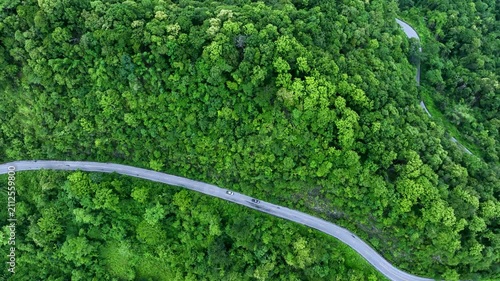 Aerial forest road with car creating abstract background for electric vehicle, ESG, sustainability and green investment business concepts.