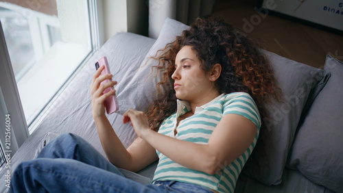 Quadro su tela Woman lying sofa scrolling phone