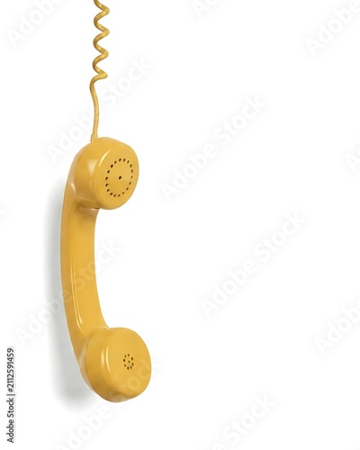 Yellow vintage telephone handset hangs from a matching curled cord on the left against white background with copy space