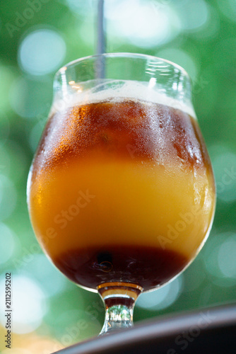 Bild auf Leinwand iced coffee with orange juice in a glass, cold refreshing summer drink with blur