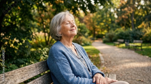Senior woman sitting on a park bench with her eyes closed and face raised, blissfully feeling the warm sunlight.