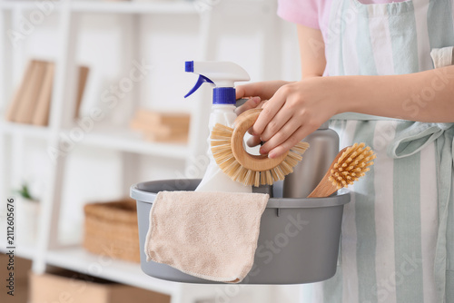 Konstfotografi Person holding a cleaning caddy with natural brushes, spray bottle, and towel fo