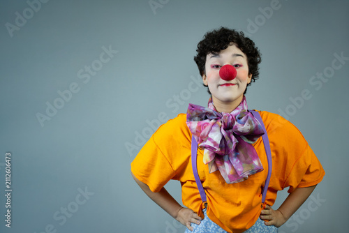 Young woman dressed as a clown, looking at camera. Horizontal studio portrait with copy space, ideal for circus art, funny character, comedian, and entertainment.