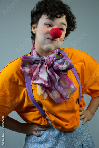 Young lady dressed as a clown, making a face. Medium shot studio portrait ideal for circus art, children's party, and fun entertainment.