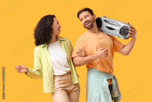 Young couple with boombox on yellow background