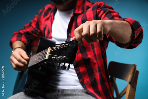 Young man tightening guitar...