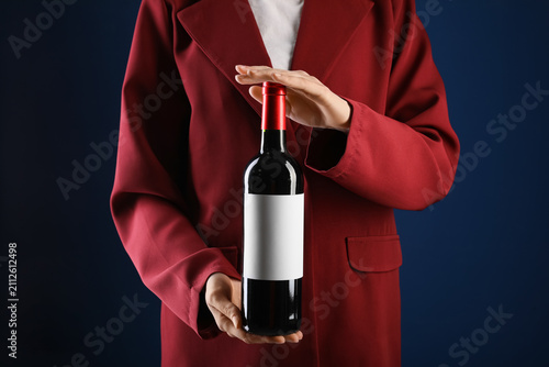Woman in suit holding bottl...