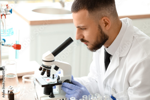 Male scientist looking through microscope in laboratory, closeup