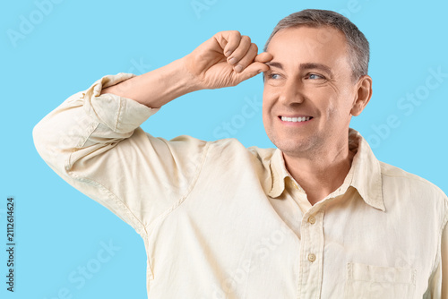Happy mature man doing face building exercise on blue background