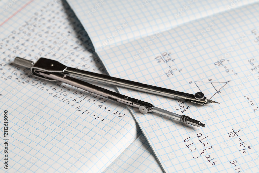 Obraz premium Copybooks with handwritten maths formulas and pair of compasses as background, closeup