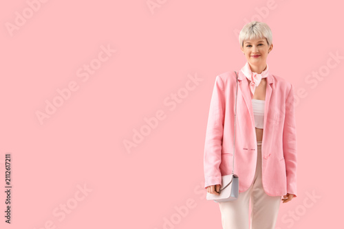 Stylish young woman with short hair and bag on pink background