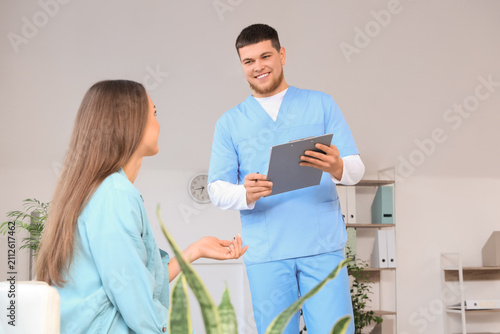 Male receptionist with waiting patient in clinic