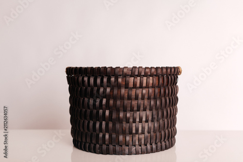 Dark brown woven basket on table against neutral background