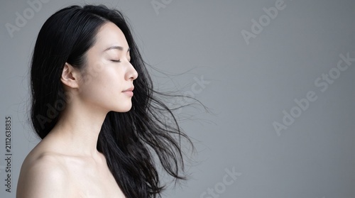 Young Japanese woman with closed eyes with a clean minimalist backdrop, cosmetics and beauty advertising concept, ideal for spa and wellness promotions
