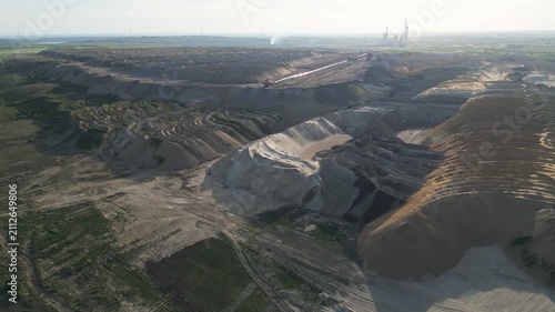Open pit coal mine landscape revealed in a slow forward drone shot on a bright sunny day.