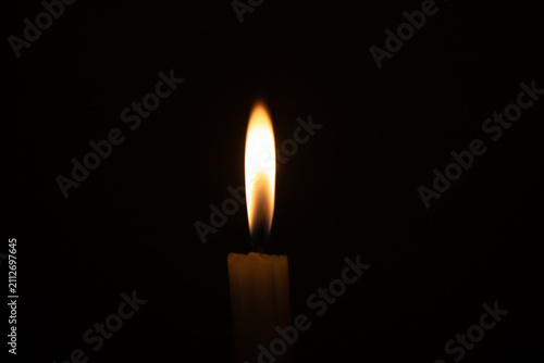 Burning candle flame isolated against pure pitch black background